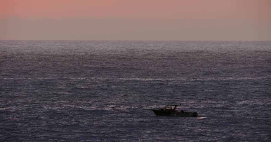 Small boat sucking in the calm waters of the ocean against a purple sky
