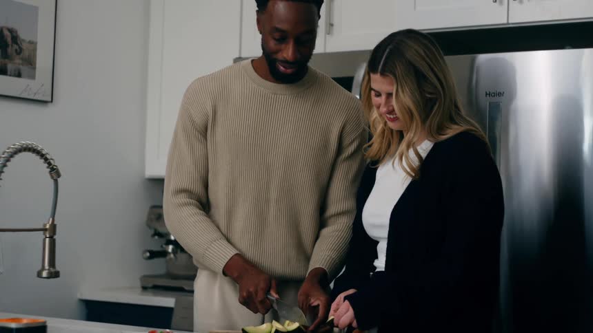 Man and woman smile while cooking together in their kitchen