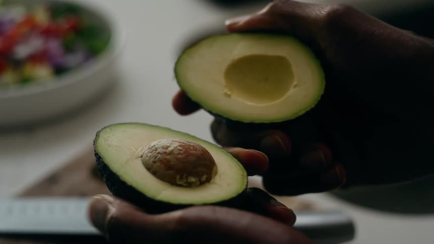 A person opens an avocado