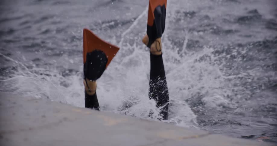 A man carrying a camera dives into the ocean