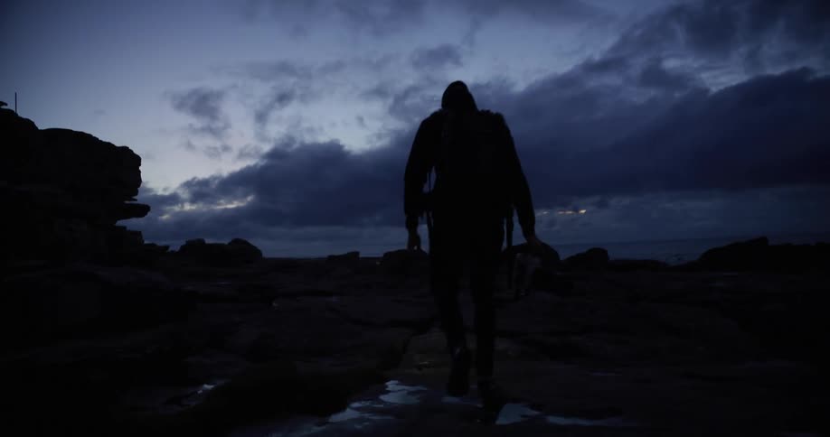 A man is hiking in the dark near the shore