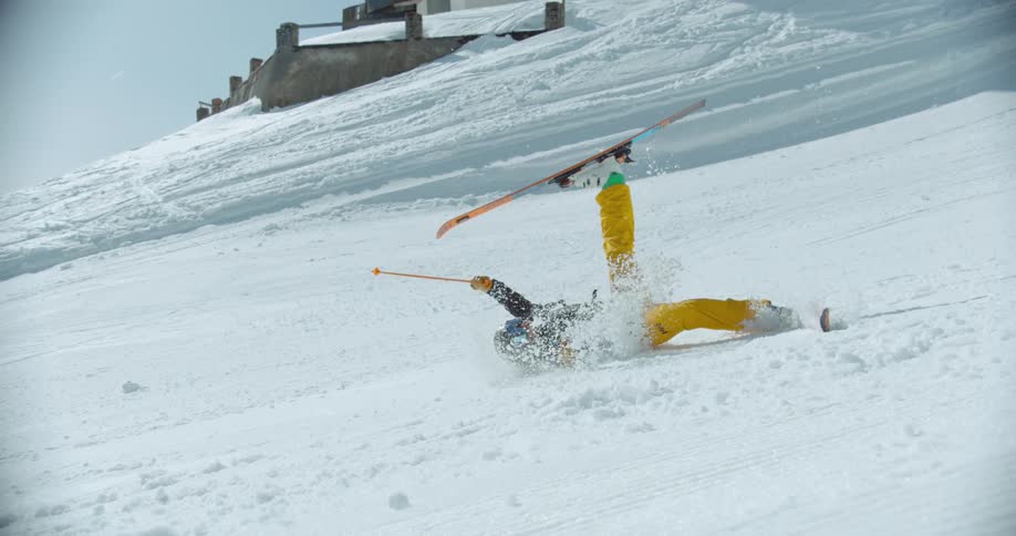 A man on skis is falling on his back on a snowy slope