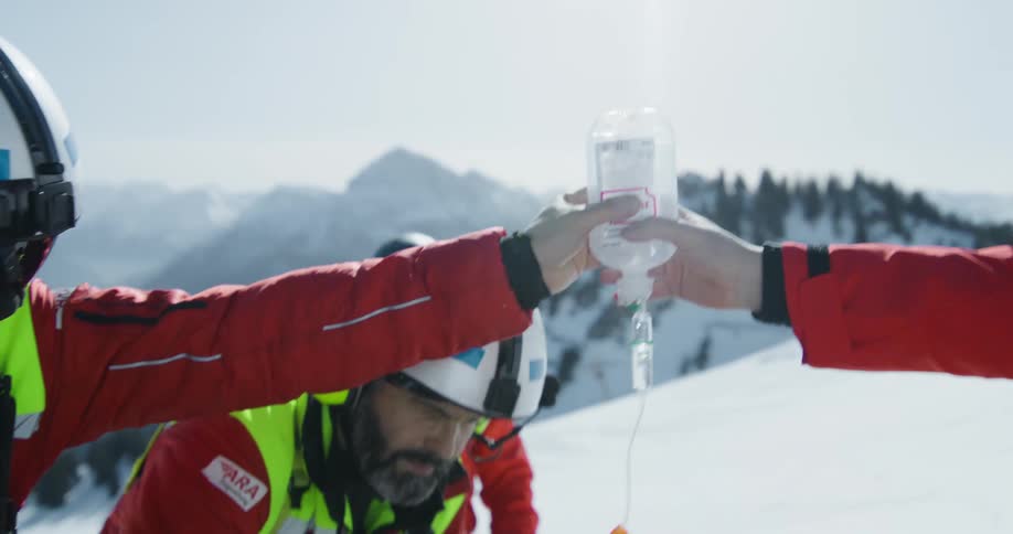 Rescue team rescues a man lying on a stretcher on a snowy mountain with iv fluid
