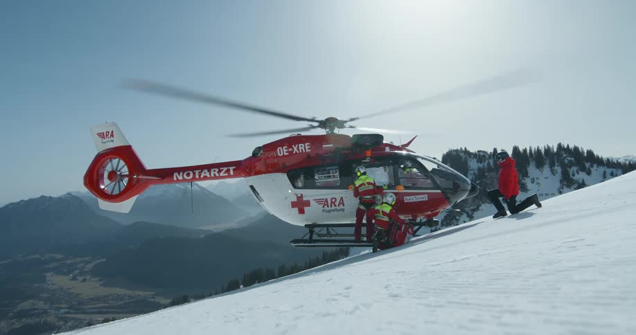 A rescue worker gets on the helicopter running on the mountain