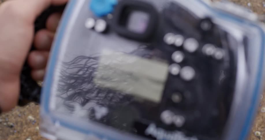 Reflection of a person with long hair on a camera encased in a waterproof housing