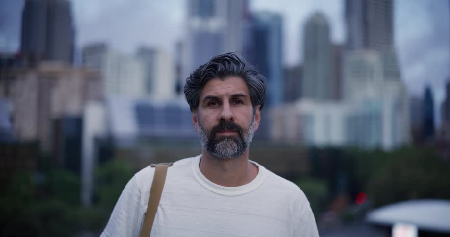 Bearded man wearing a white t shirt on the streets of a metropolis during day time