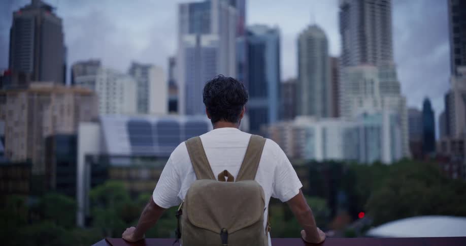 A man looks out over the balcony at the skyline