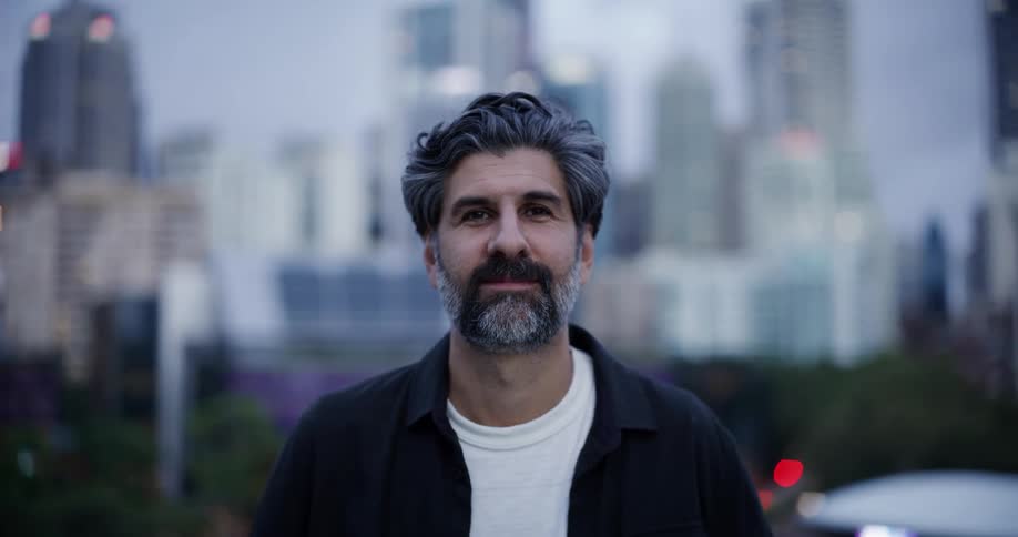 A man with a beard slowly smiles