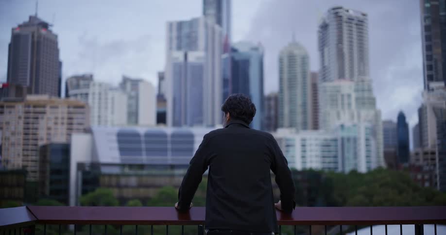 A man leans on the railing looking over the skyline