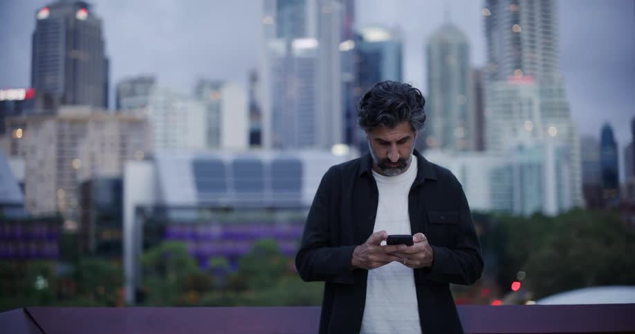 A man is using his cell phone on the balcony