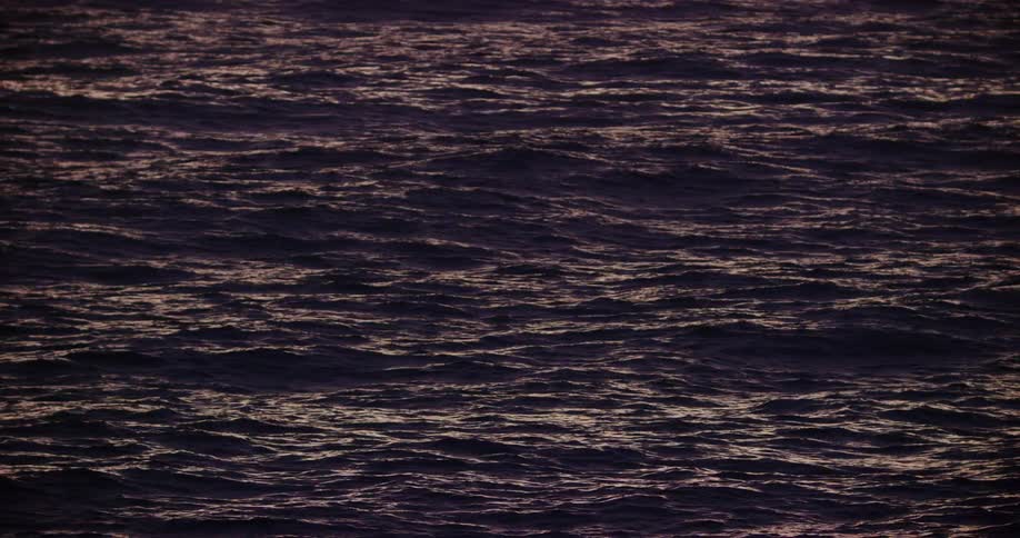 The surface of a sea with some ripples of waves moving in the evening
