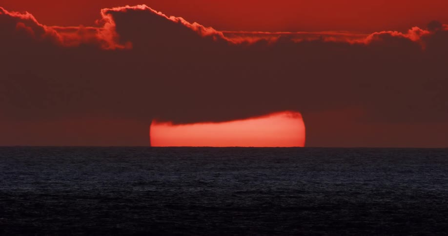 Clouds passing in front of the sun over the ocean during dusk or dawn