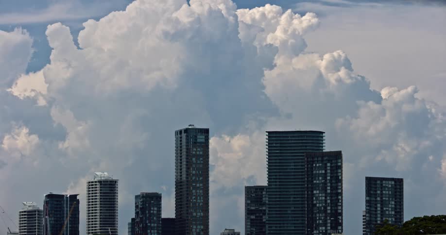 A large dramatic cloud looms over a cityscape of tall modern buildings