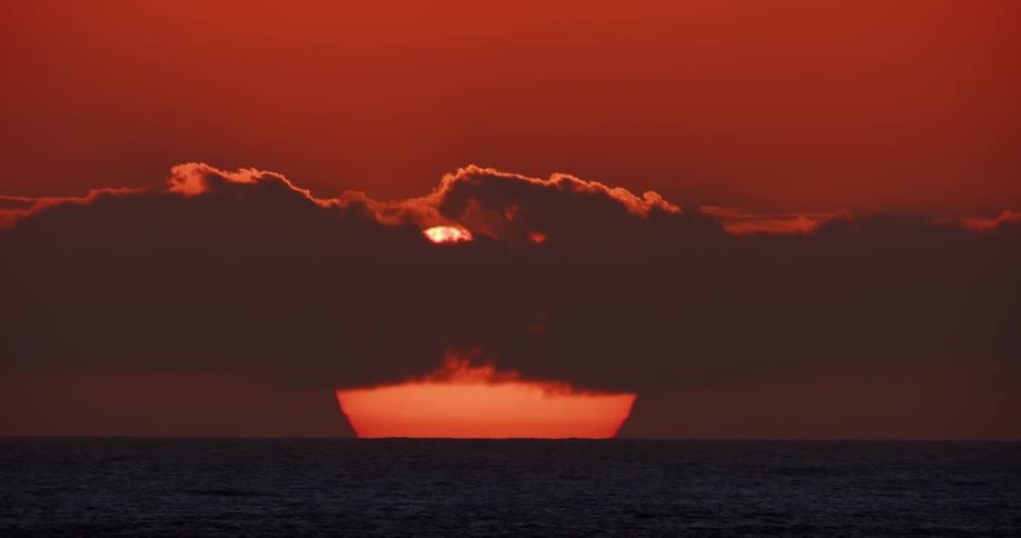 Cloud passing in front of the sun over the ocean during dusk or dawn