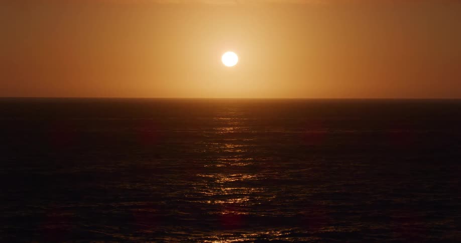 Water slowly rolls in an ocean at sunset