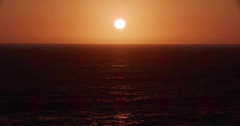 The sun is slowly rising over the ocean