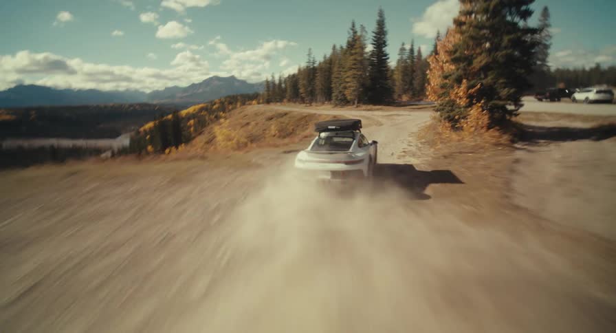 Car speeding through a dusty mountain road surrounded by trees outdoors during day time