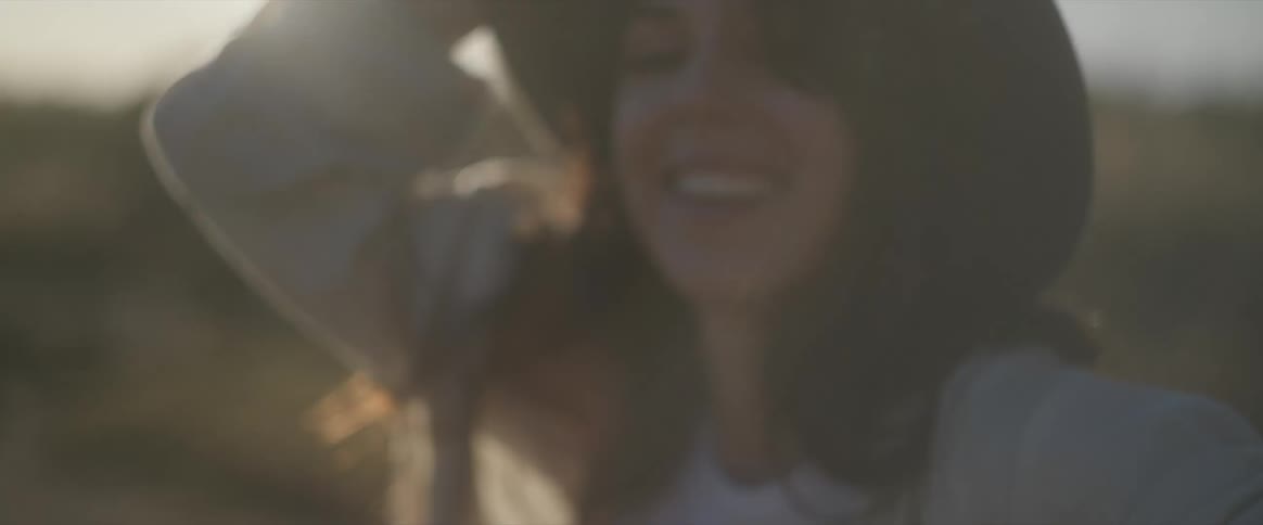 A young woman wearing a hat and she is smiling and giving a twirl