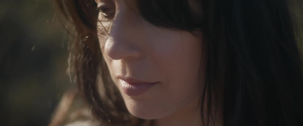 Dark haired woman outdoors surrounded by vegetation during day time