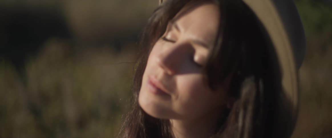 Portrait of a young woman with a sun hat and closed eyes enjoying the moment in a field