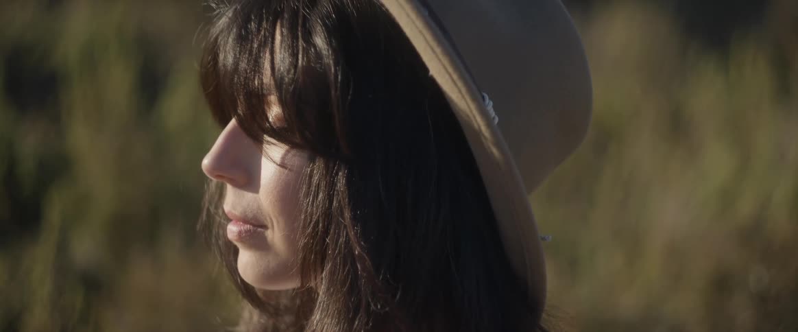 The face of a young woman wearing a hat and her hair is partially covering her face