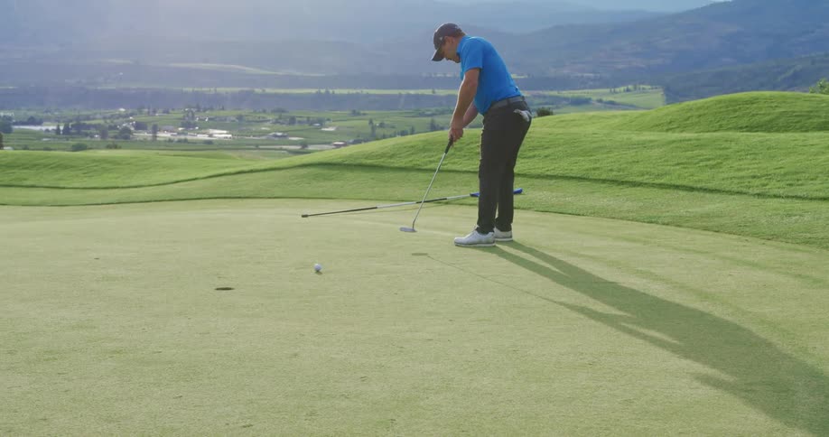 A man is putting on the green of the golf course