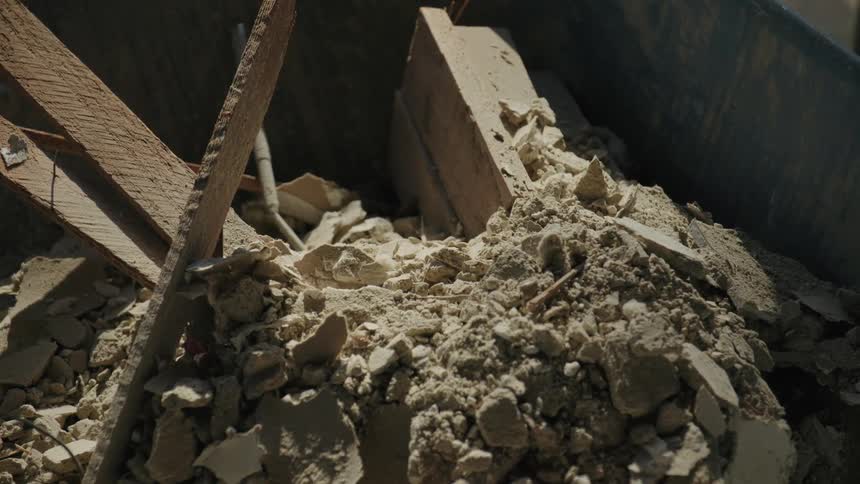 A wheelbarrow filled with rubble dust broken pieces of brick and wood and other debris from a demolition or construction project
