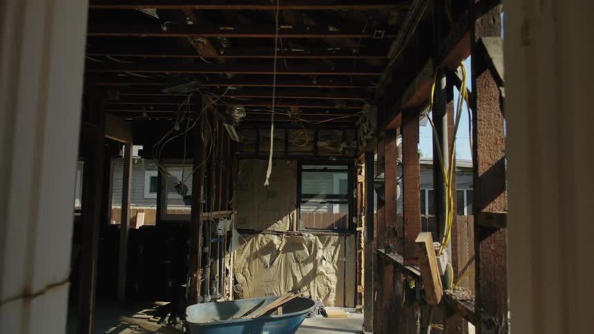 A view through a doorway reveals a partially constructed or renovated room with exposed wooden beams