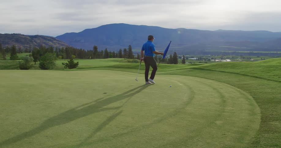 A man carries the flag away from the golf hole