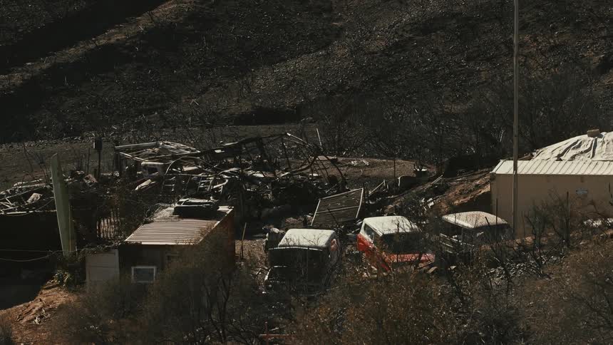 Old cars parked in a junkyard surrounded by mountains