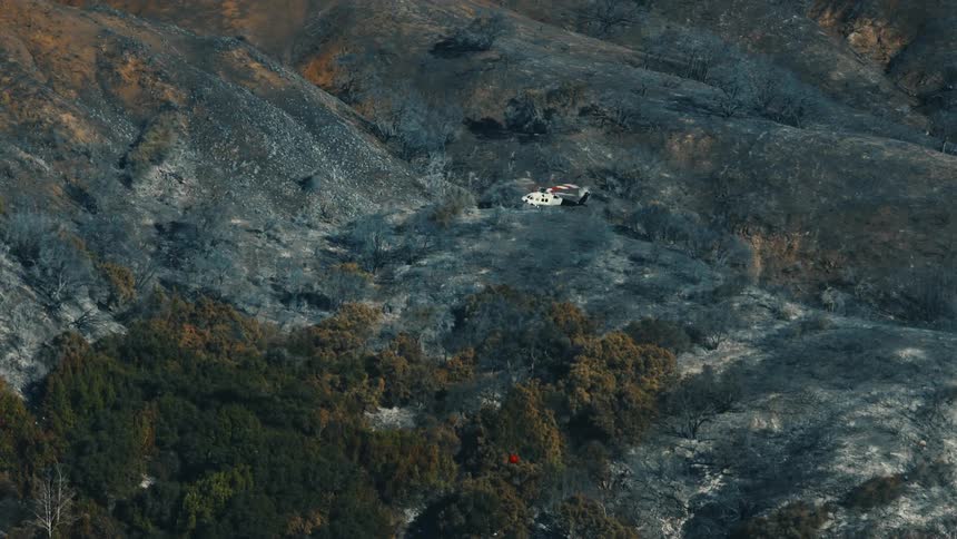 A rescue helicopter flies high over the hills