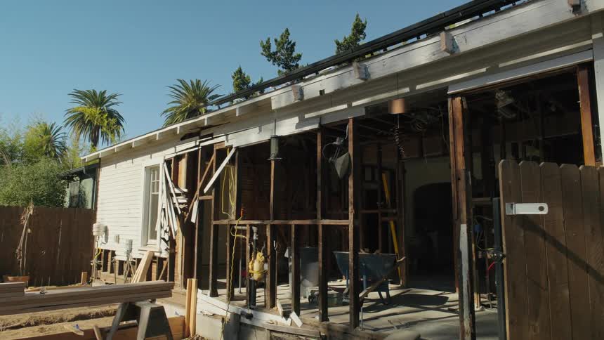 Unfinished house filled with tools and materials for construction surrounded by trees outdoors during day time