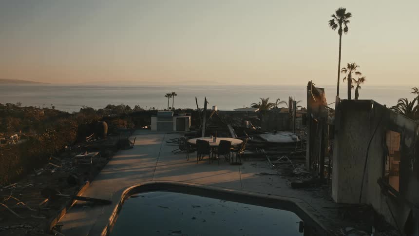 Charred homes surround a swimming pool on a hillside overlooking the ocean
