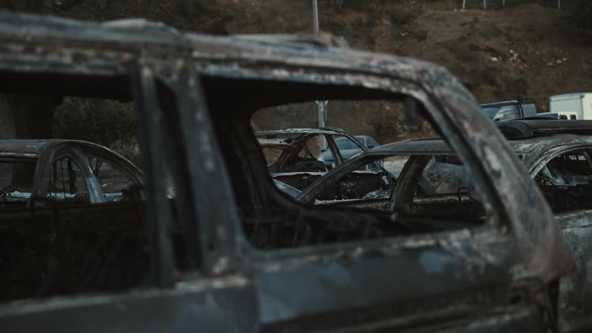 Multiple burnt car wrecks occupy the same parking lot as undamaged vehicles