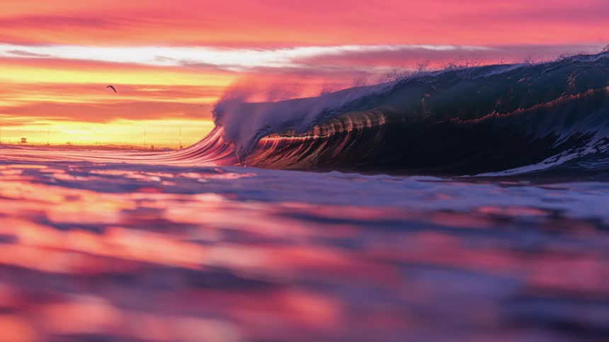 Large tubular wave breaking in the sea against a reddish sky