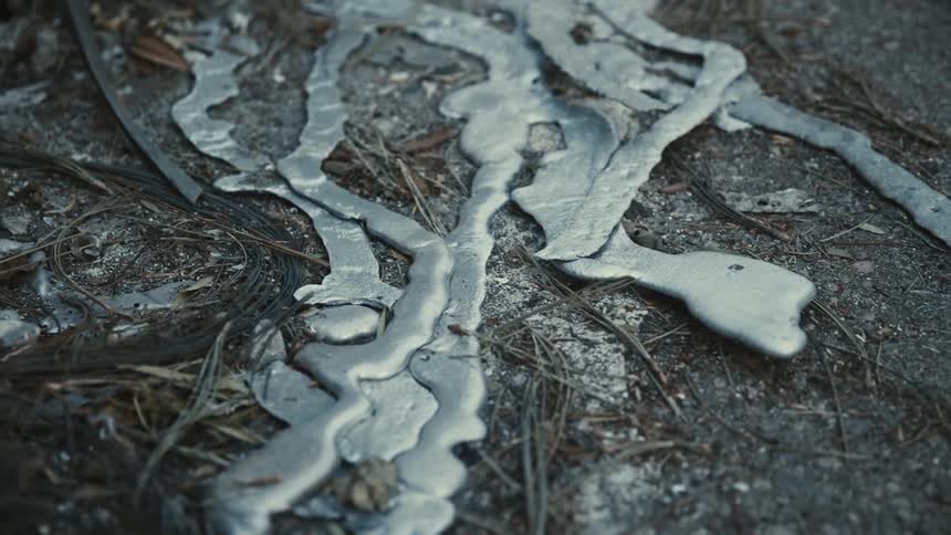 Molten strips of metal over a concrete floor outdoors during day time