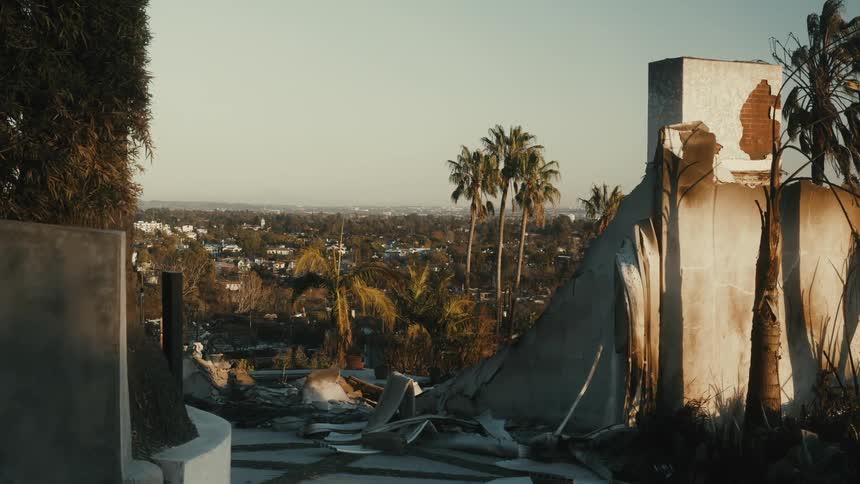 Street on a hill with destroyed houses and a residential neighborhood in the background