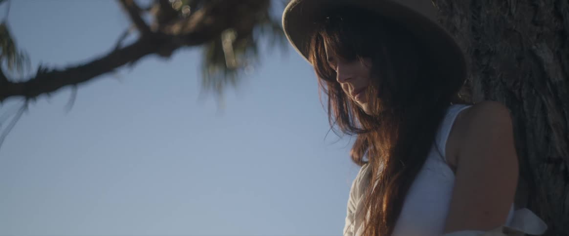 A woman is leaning against a tree