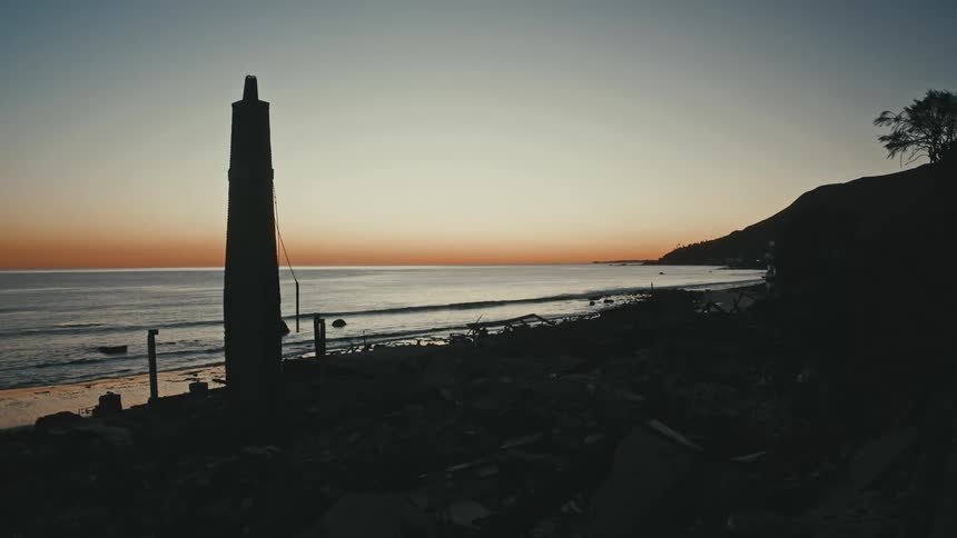 A lone chimney of a house stands among debris from the 2025 Malibu fires on Pacific Coast Highway