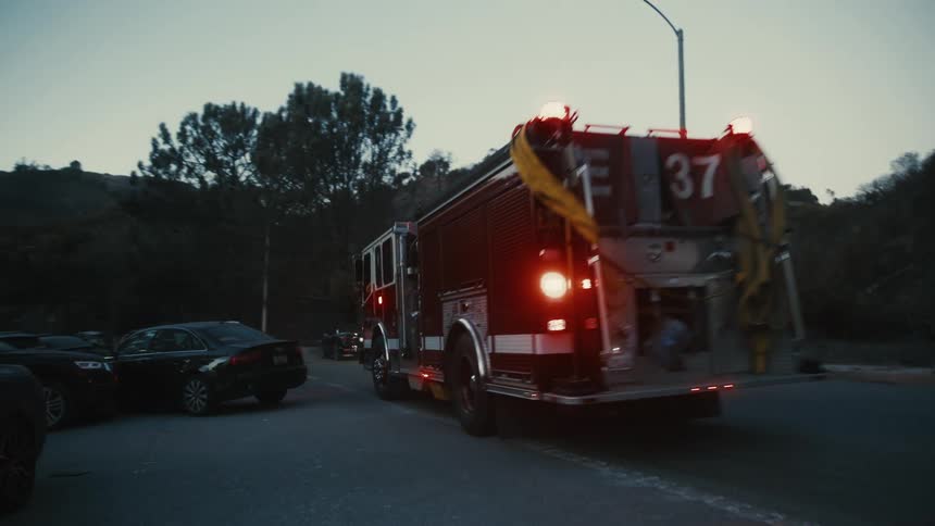 Fire truck with lights on driving down a road