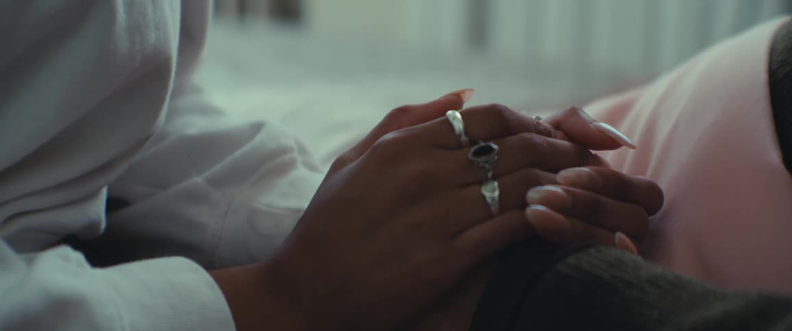 Woman holds the hand of a person lying on a bed