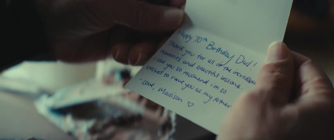 A pair of hands opens a greeting card that reads happy 70th birthday dad and includes a personal message from madison