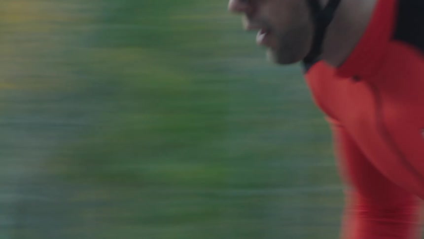 Man pedals quickly while cycling past the woods on an autumn day