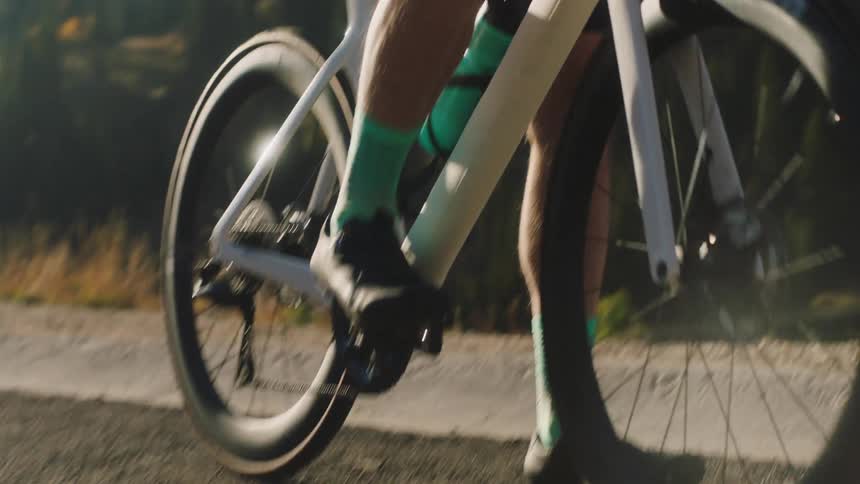 A cyclist in red is shown riding a bicycle with close ups of the legs and feet pedaling