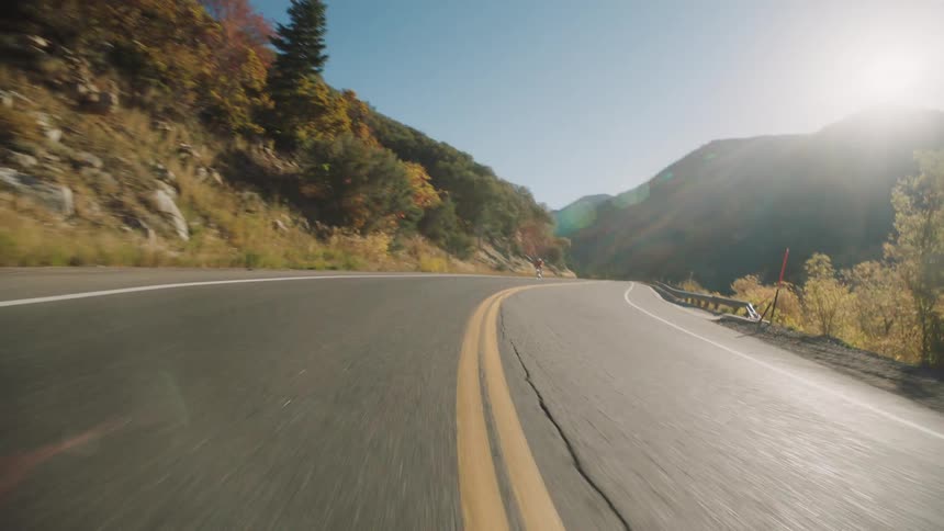 Cyclist riding at high speed on a highway surrounded by mountains