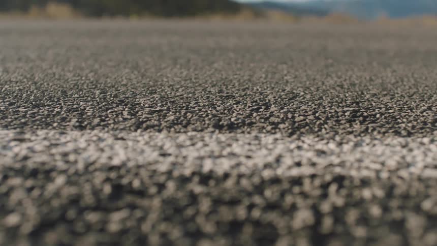 A painted line is seen on an old asphalt road