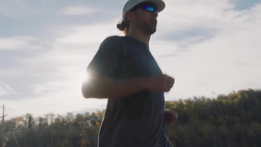 Man in cap and glasses running outdoors