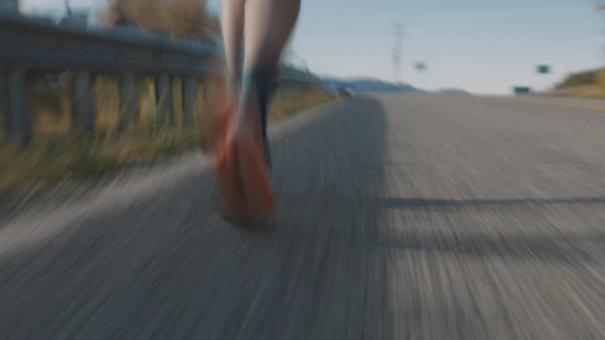 A man runs along an asphalt road on a partly sunny autumn day