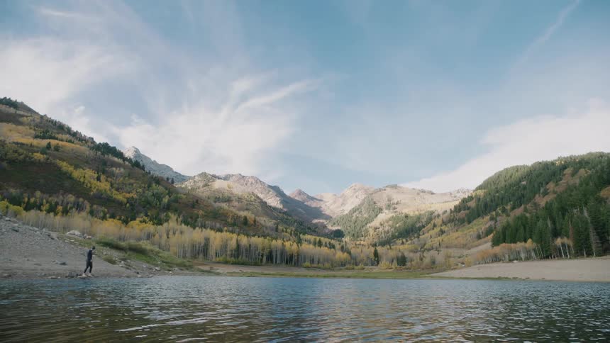 A man steps into a lake in the mountains