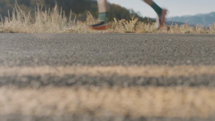 Feet of a person running on asphalt outdoors